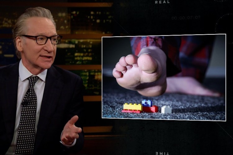 Bill Maher talks as a foot steps on a Lego