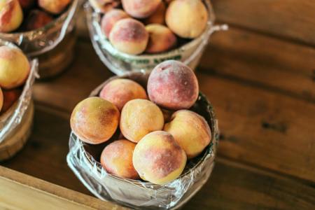 four buckets full of peaches on a wooden table