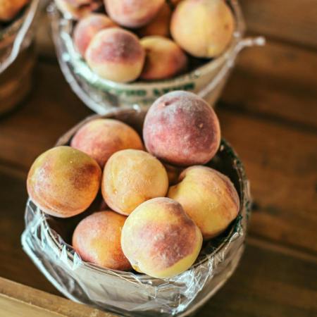 four buckets full of peaches on a wooden table