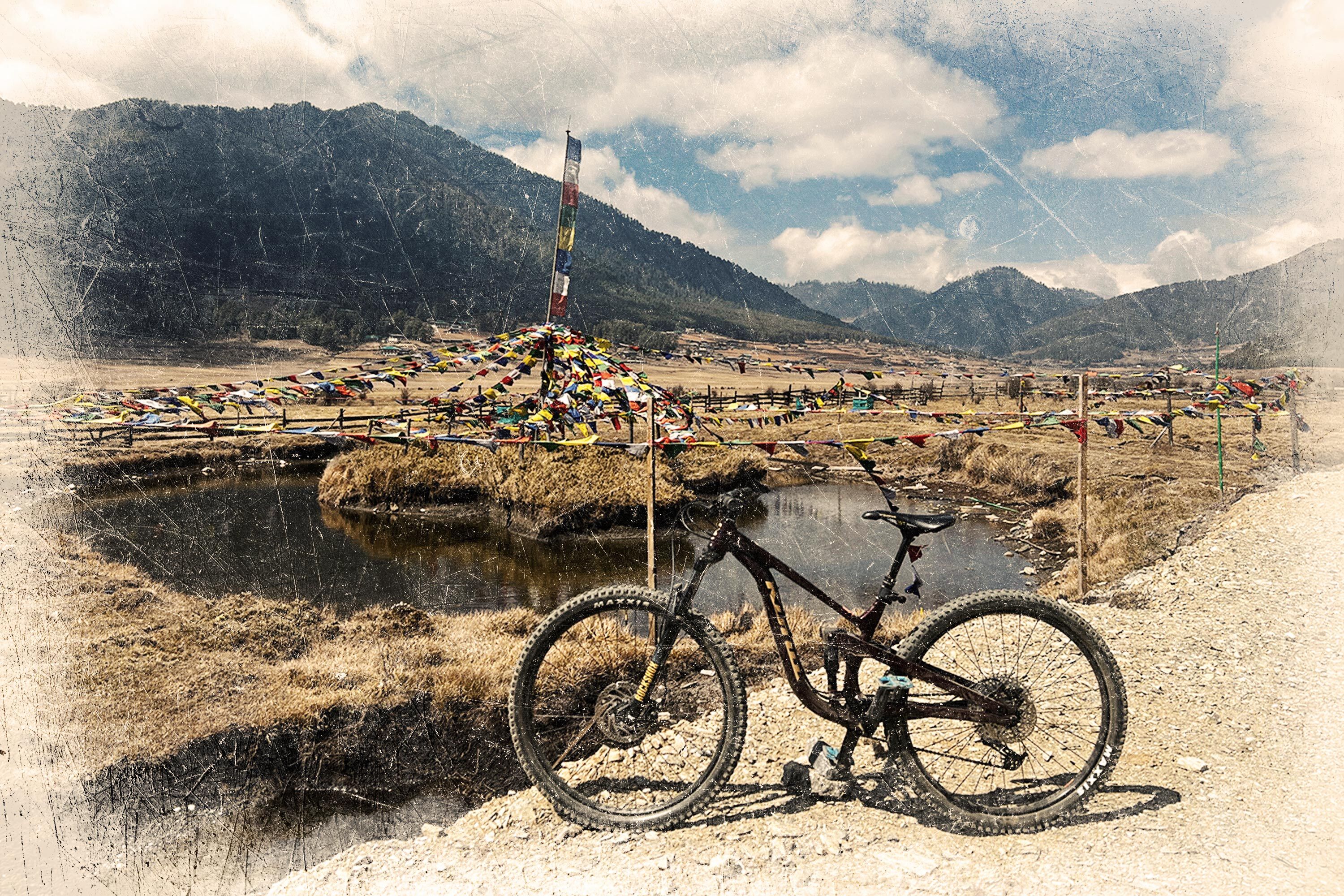 A bike positioned in front of prayer flags in Bhutan.