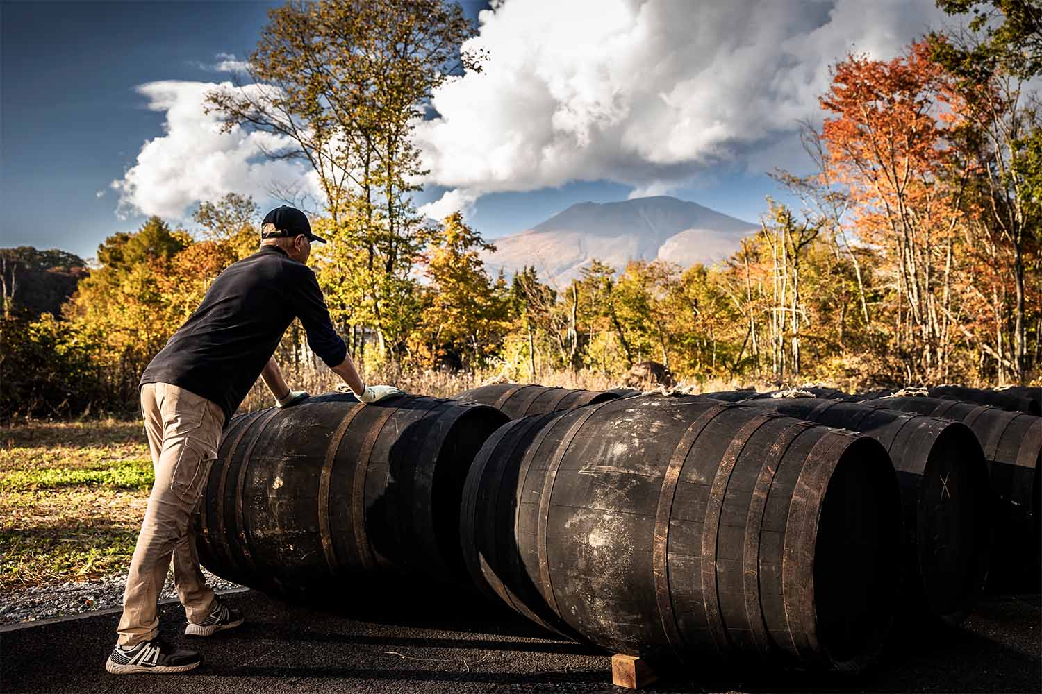 The new distillery is in the town of Karuizawa, near an active volcano. The master distiller is shown here moving barrels outside.