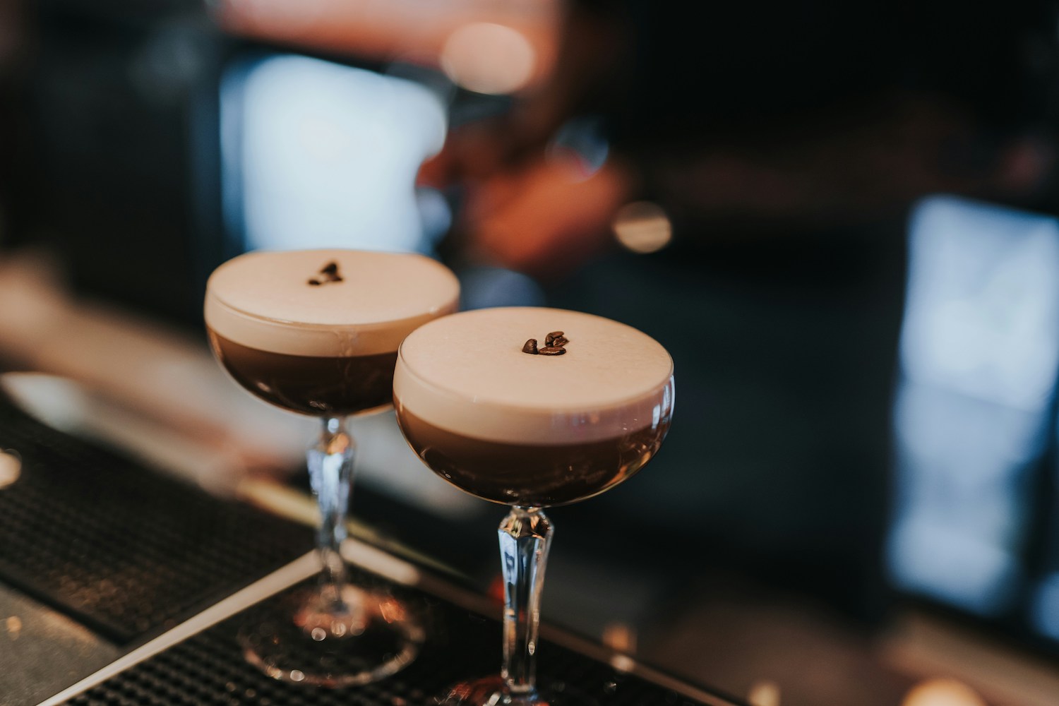 two espresso martinis sitting on a bar mat