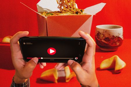 A person holding up their phone and watching YouTube while they eat