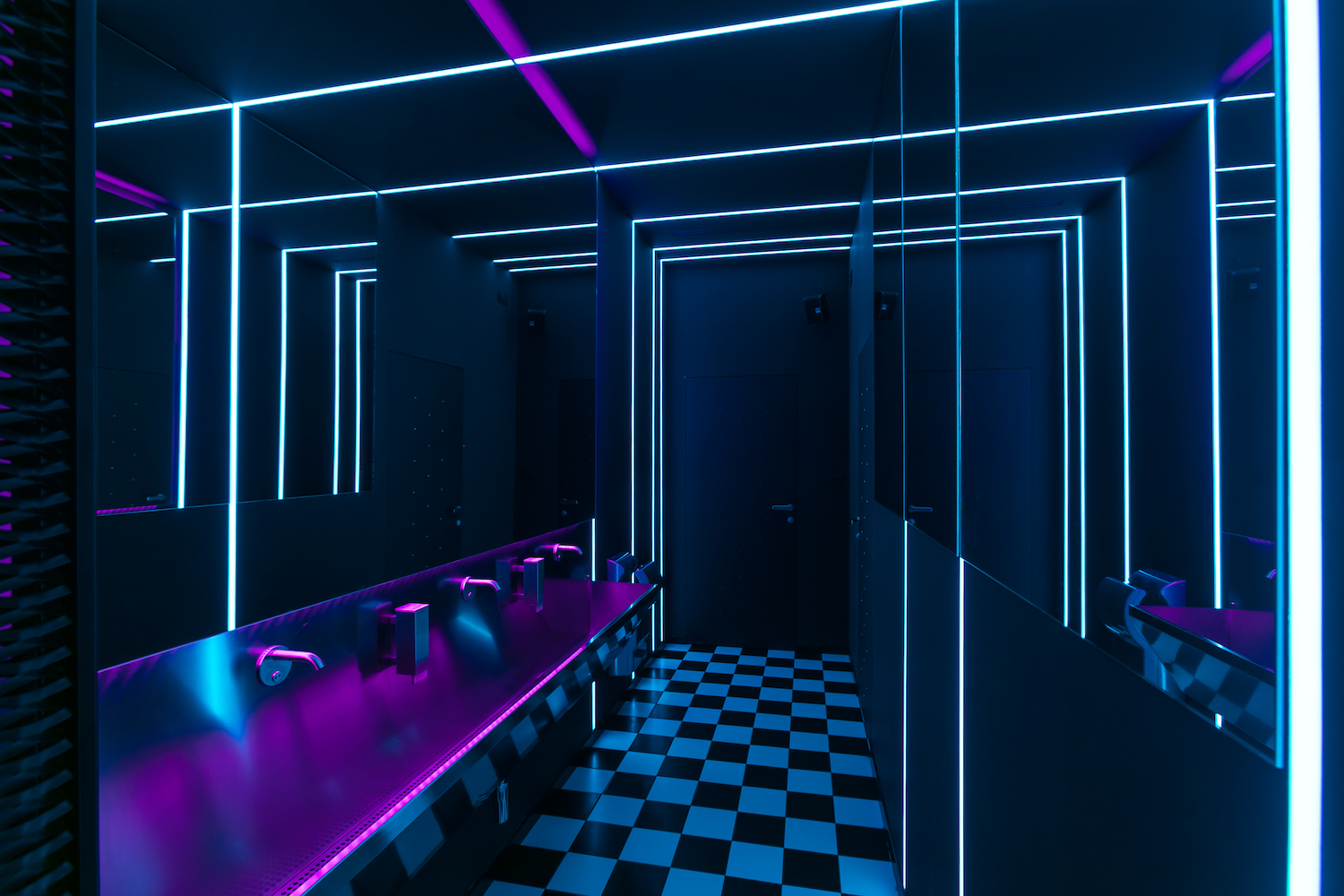 a bathroom with a black and white checkered floor and neon purple lights