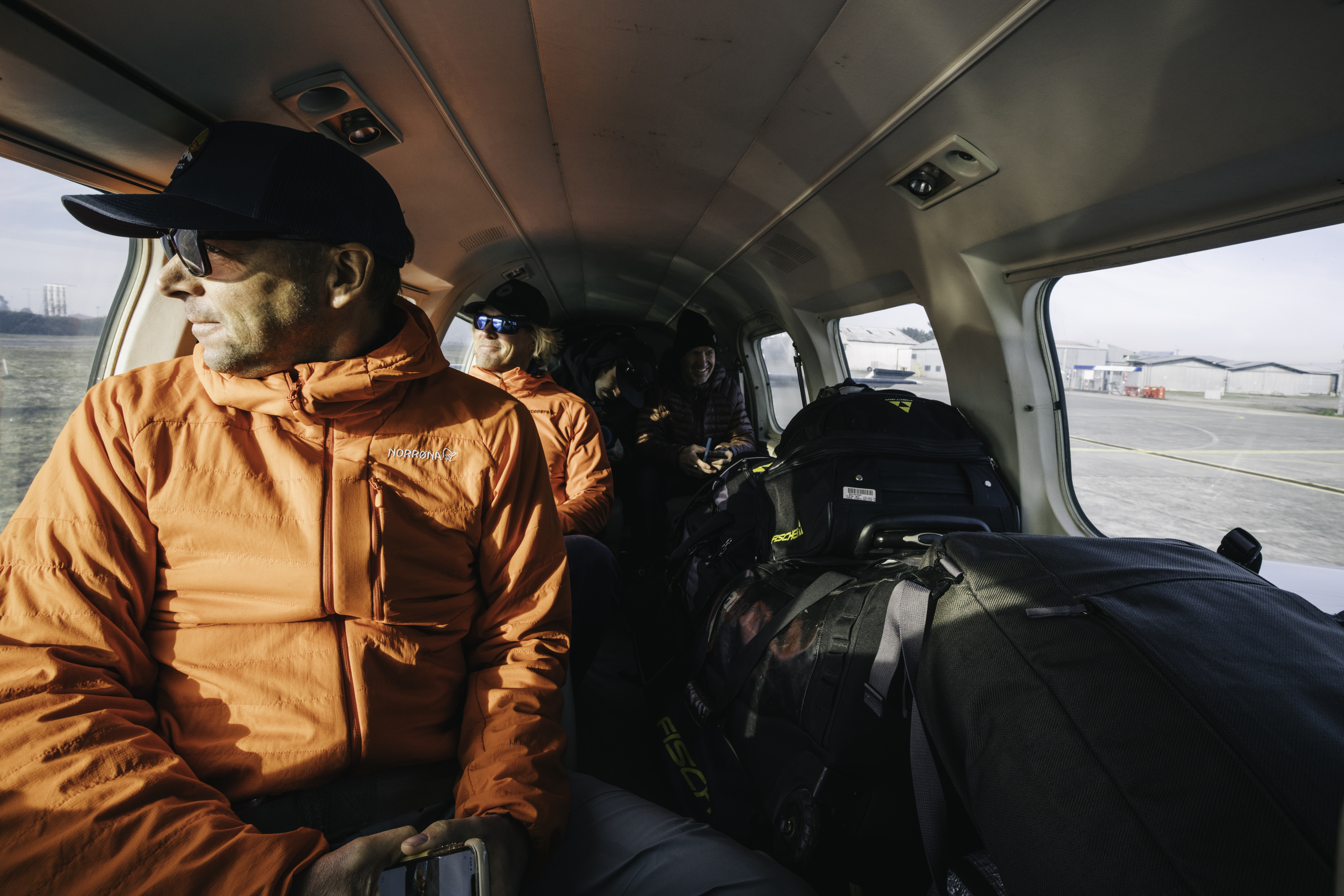 A man in an orange hacket looks out the window of a cockpit.