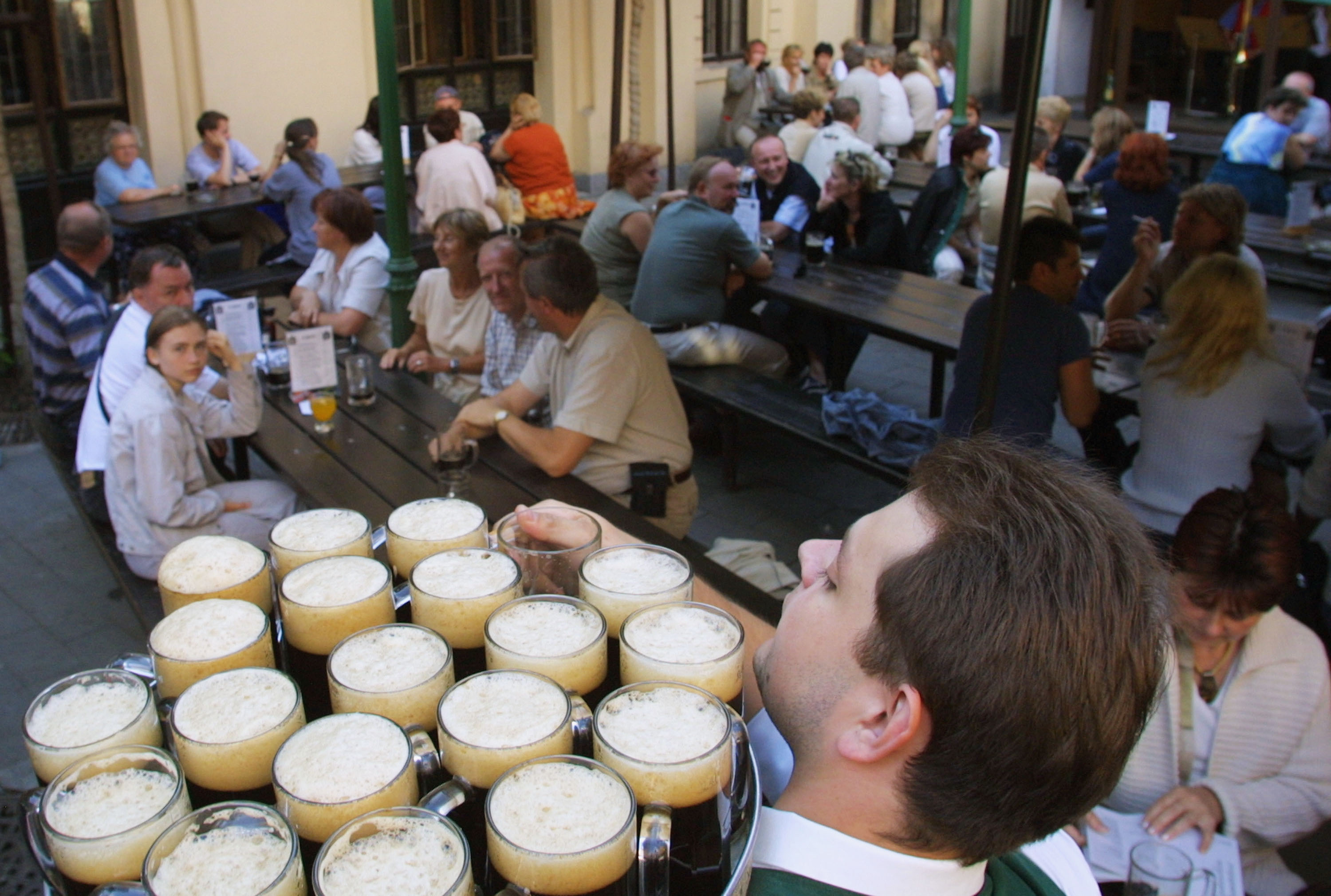 PRAGUE, CZECH REPUBLIC - JUNE 21: A waiter distributes glasses of dark beer to tourists June 21 at the famed U Fleku pub in Prague, Czech Republic. Pub life and beer are an intrinsic element of Czech culture, and contribute to the Czech Republic's first place world ranking in annual consumption of beer per capita, at 156 liters, well ahead of second-place Ireland (125 liters per head) and third-place Germany (120 liters per head).