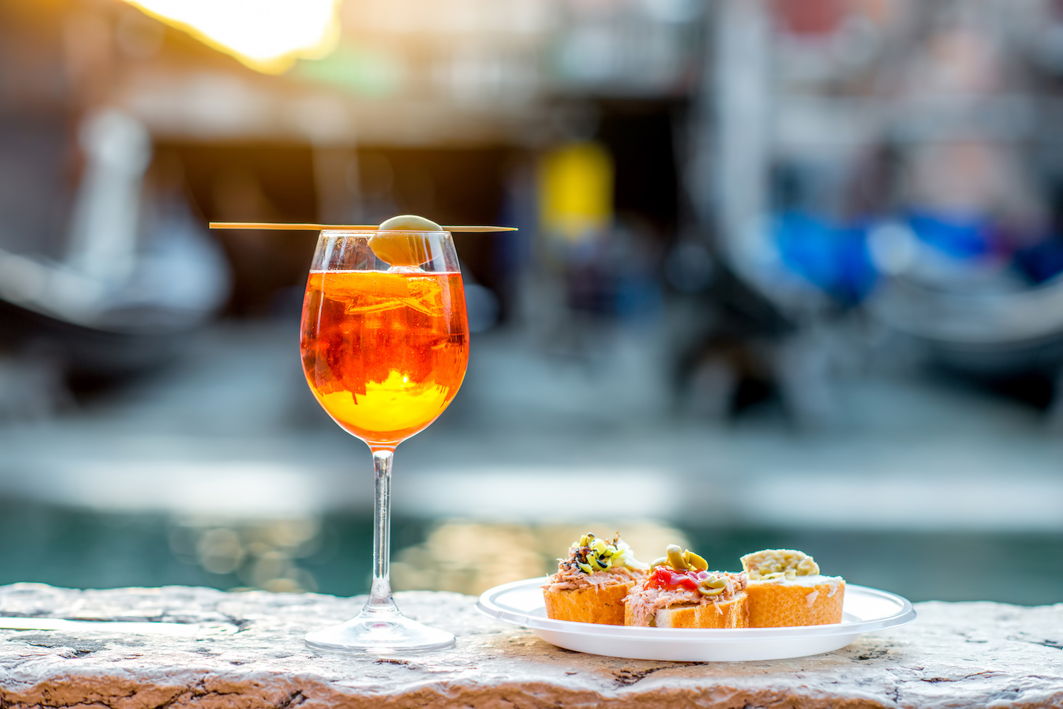 Spritz Aperol drink with venetian traditional snacks cicchetti on the water chanal background in Venice