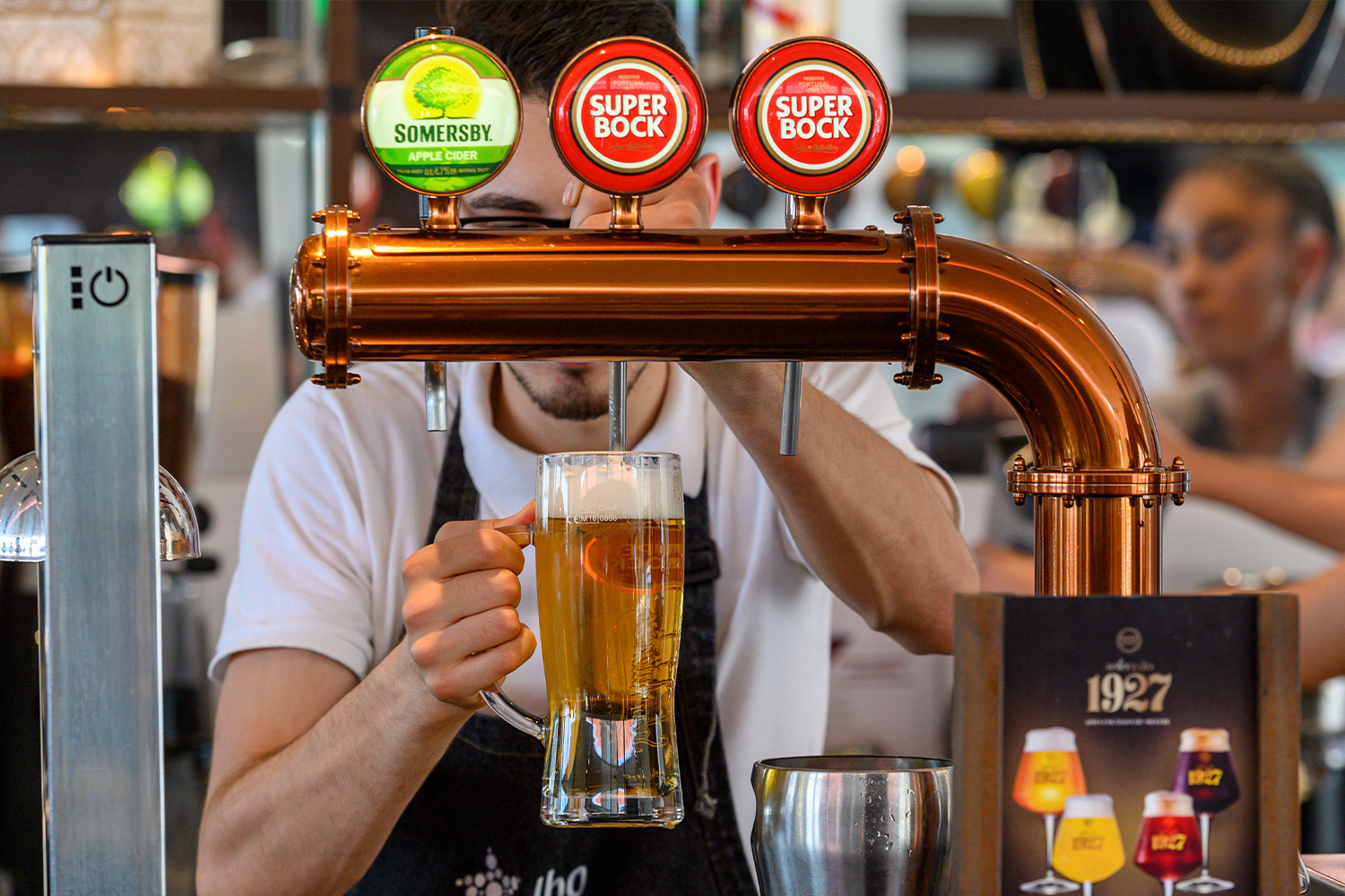 a bartender pouring a super bock beer from a tap