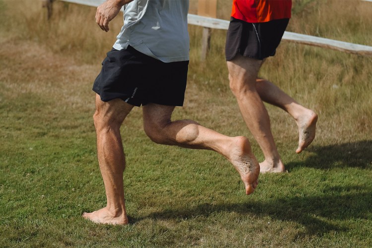 Two men running barefoot on turf. Here's why the natural ground is the best "exercise equipment."