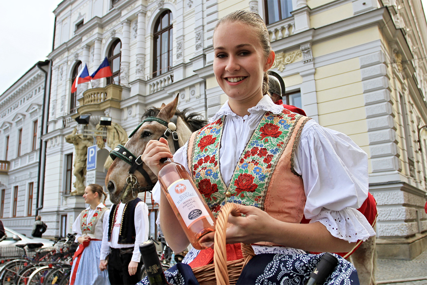 A woman holds a bottle of St Martin wine as a man representing Saint Martin sits on a horse at Masaryk square in Uherské Hradiste, Czech Republic, on Martinmas