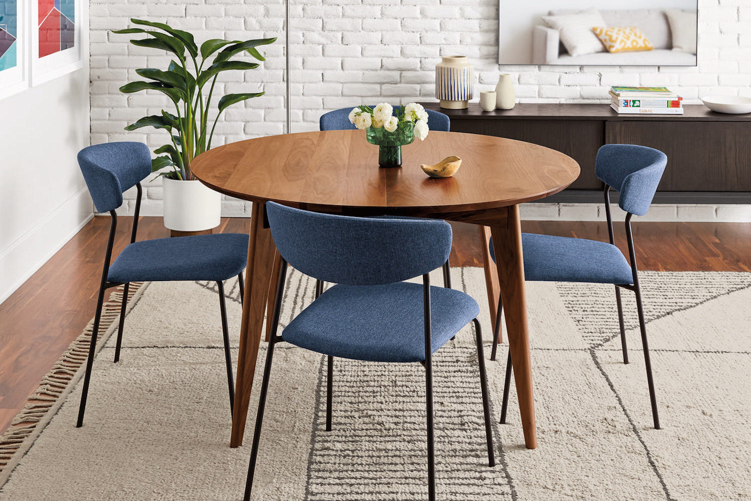 a round mid-century walnut wood table with blue upholstered chairs