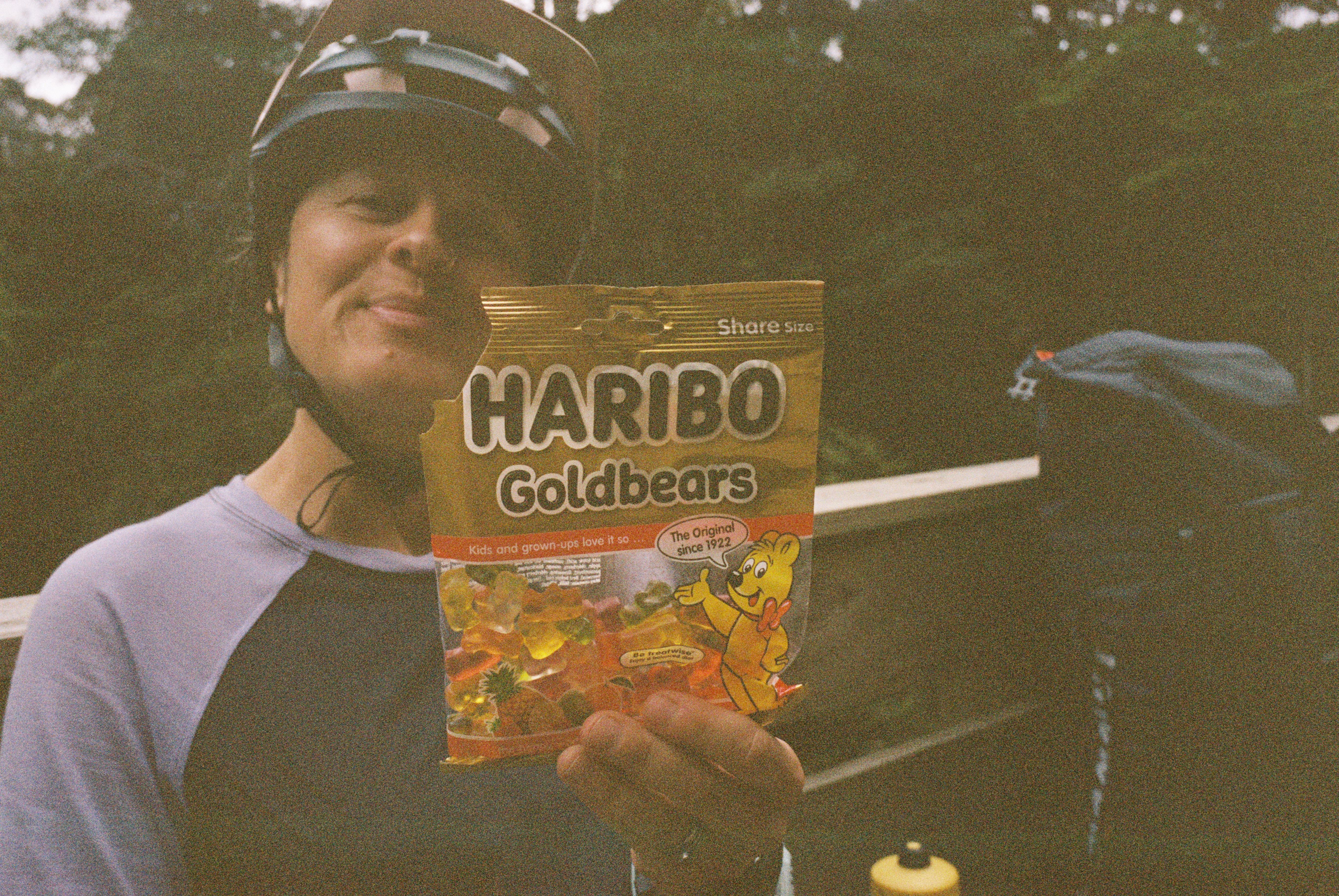 A woman with a bike helmet holds Haribo Goldbears up to the camera.