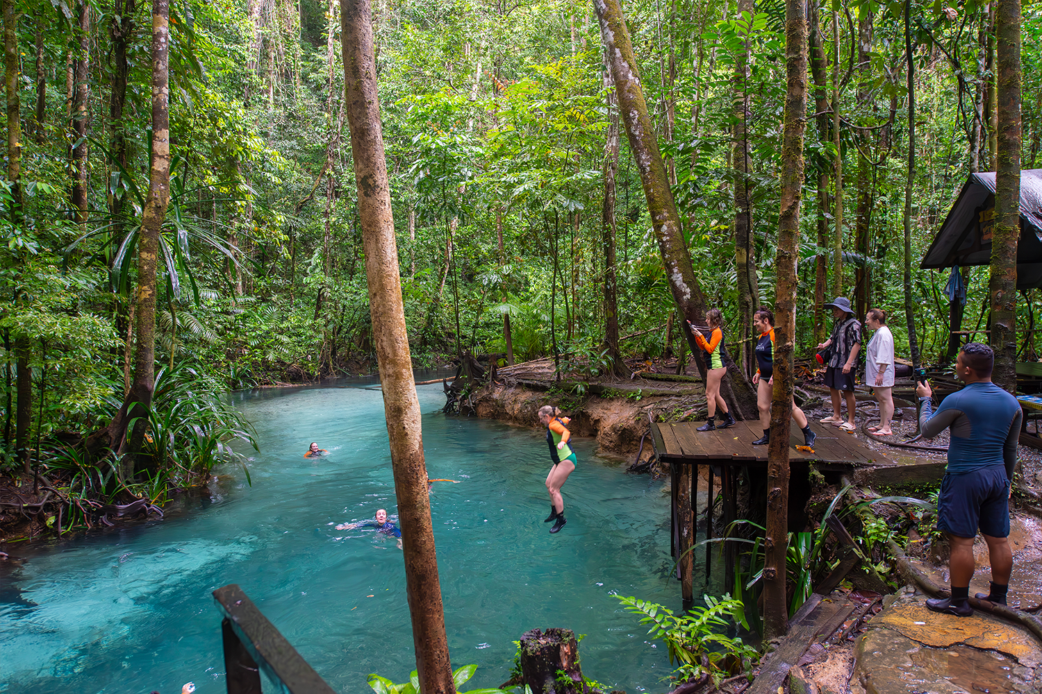 Leaping into the glowing, electric blue waters of the freshwater river Kali Biru