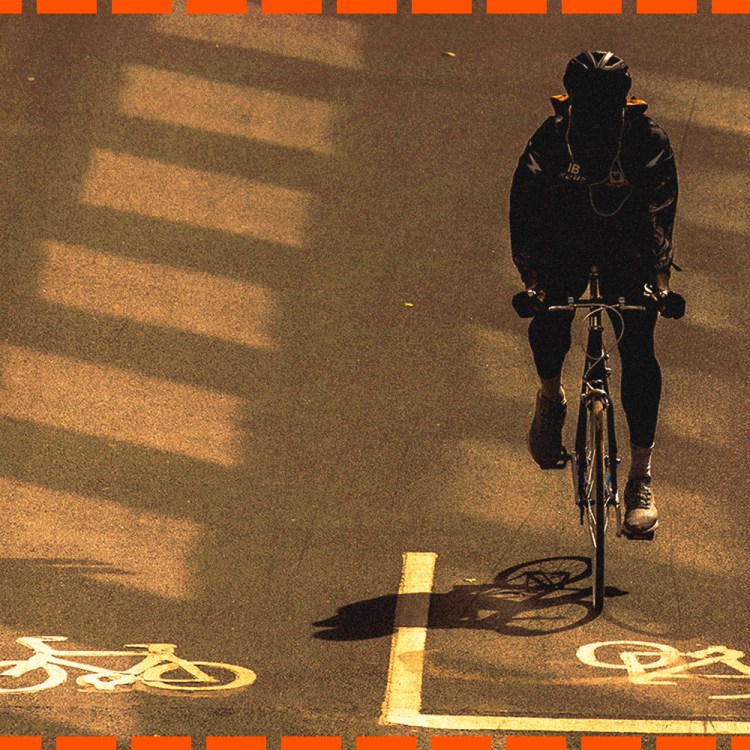 A cyclist in a bike lane, tinted in sepia, with orange jotted lines around the border.