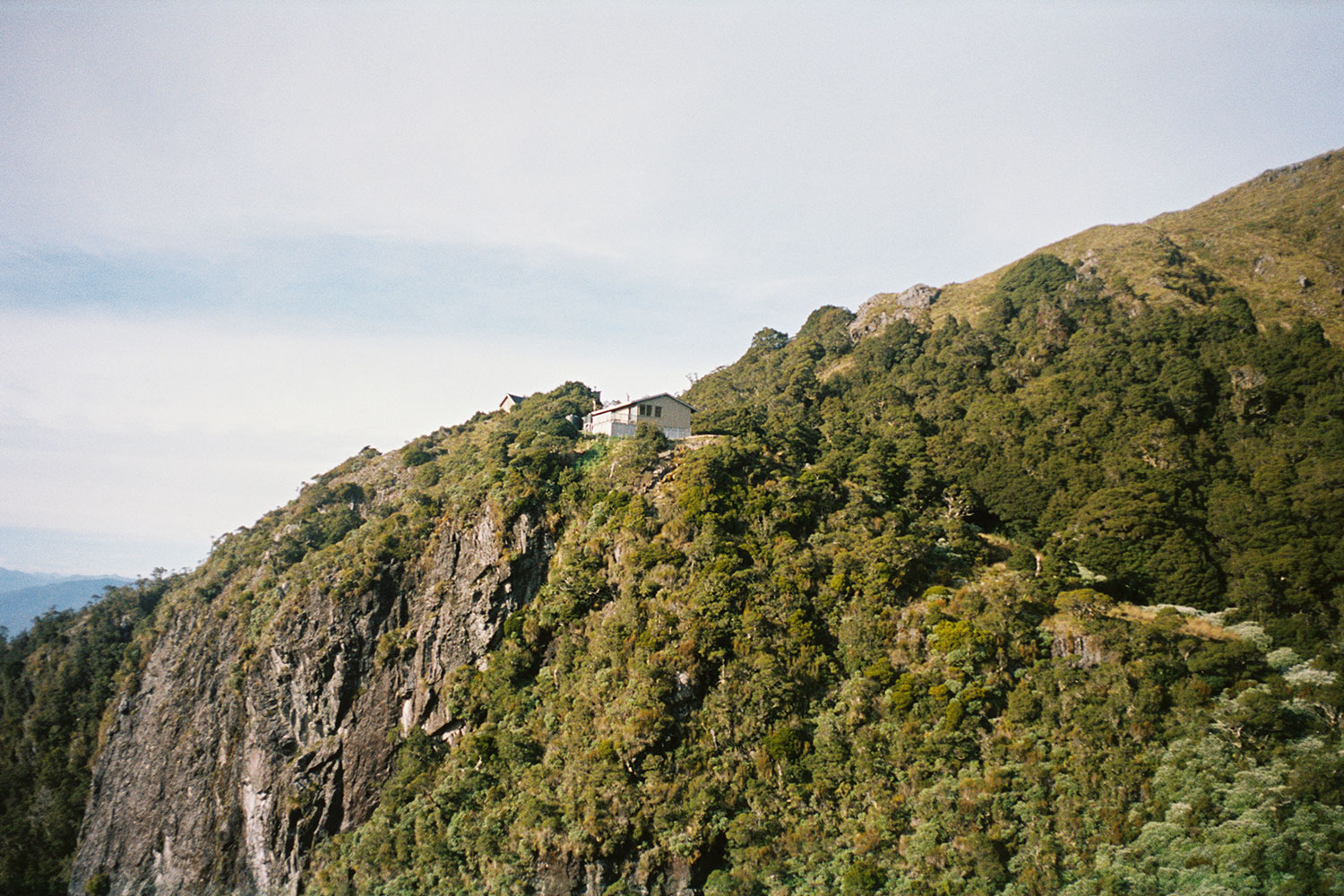 A view of a small hut on a green cliff.