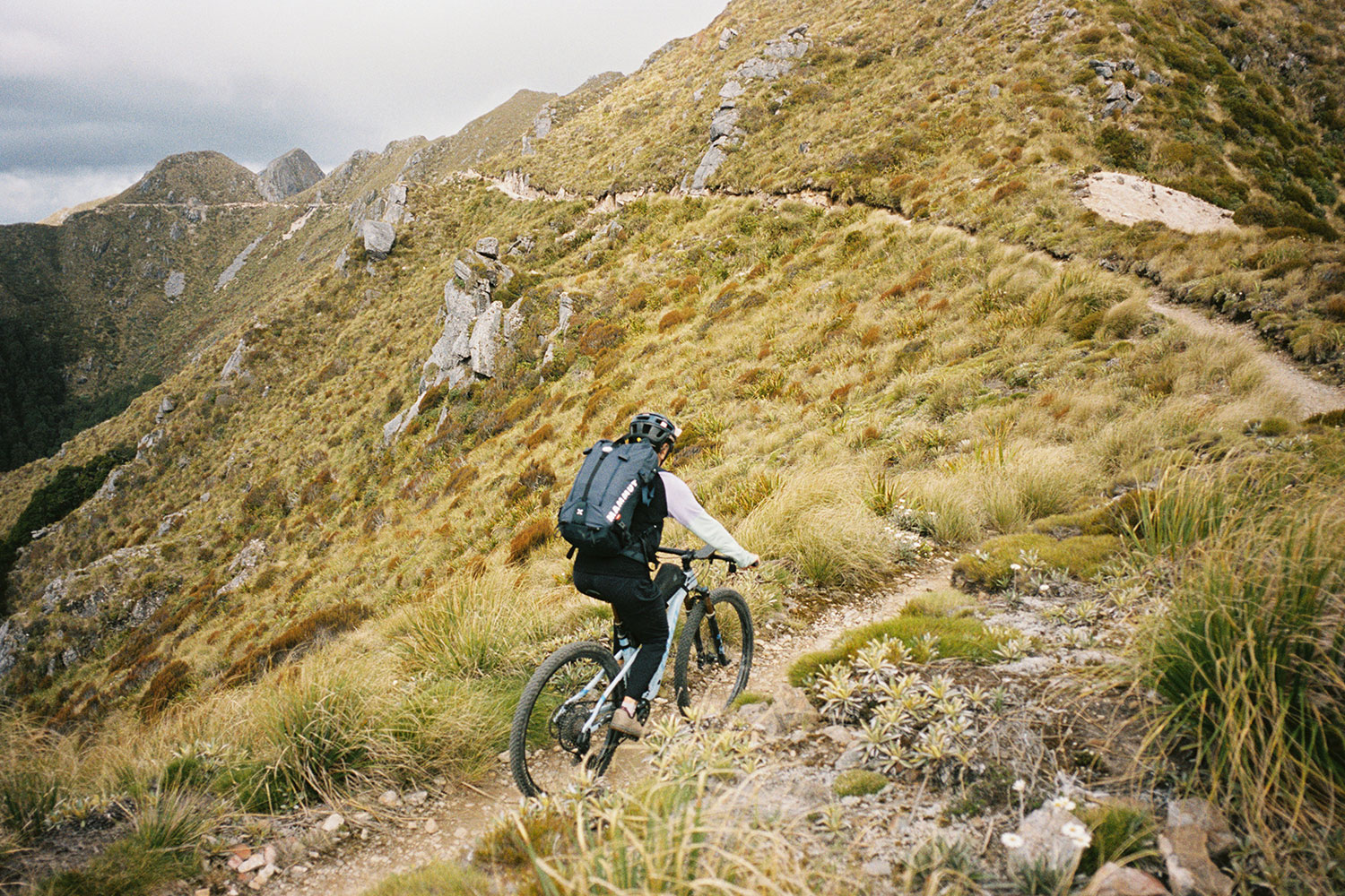 A cyclist making their way up a hill, wearing technical pants and a jacket.