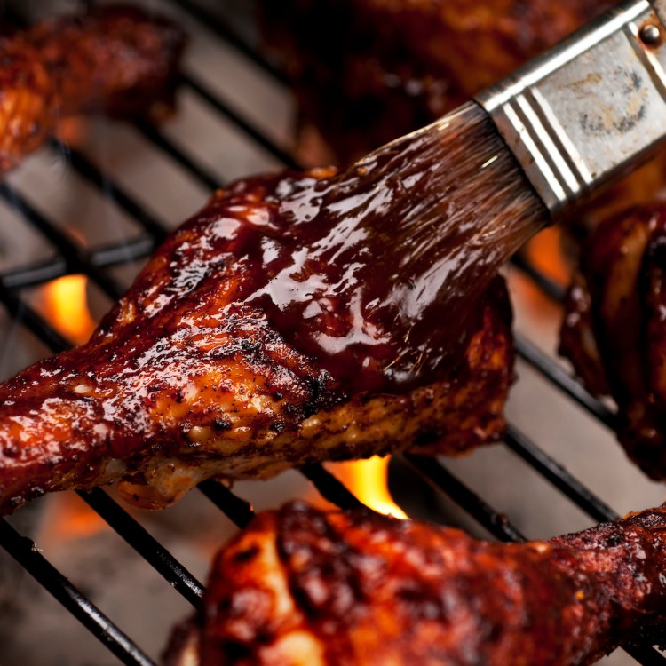 Chicken legs on the grill with barbecue sauce.