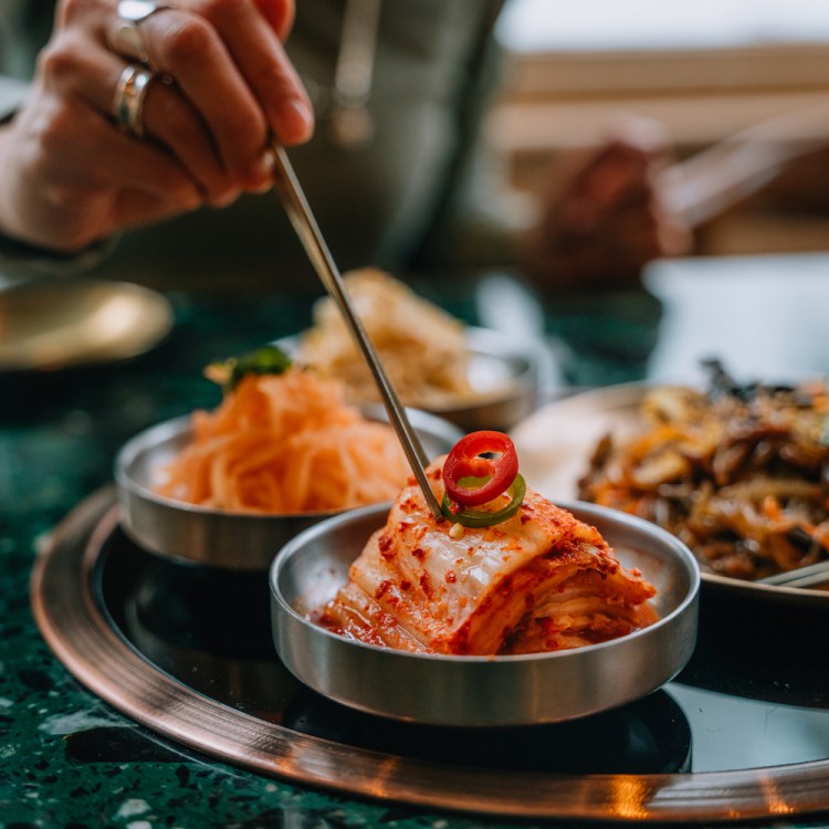 Woman enjoying traditional Korean fermented vegetables (Banchan) with chopsticks