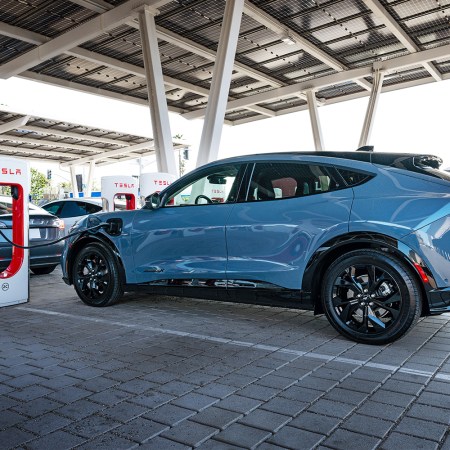 Ford Mustang Mach-E electric SUV charging at a Tesla Supercharger